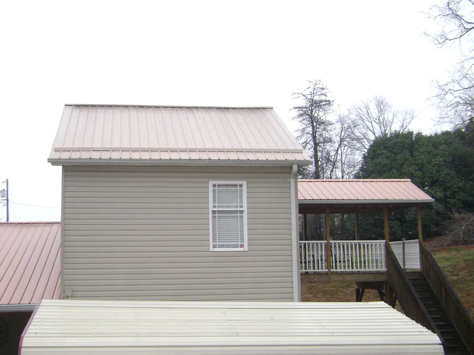 Tan metal roofs on a two story addition and attached porch, from a Roof Replacement job in Cottonwood