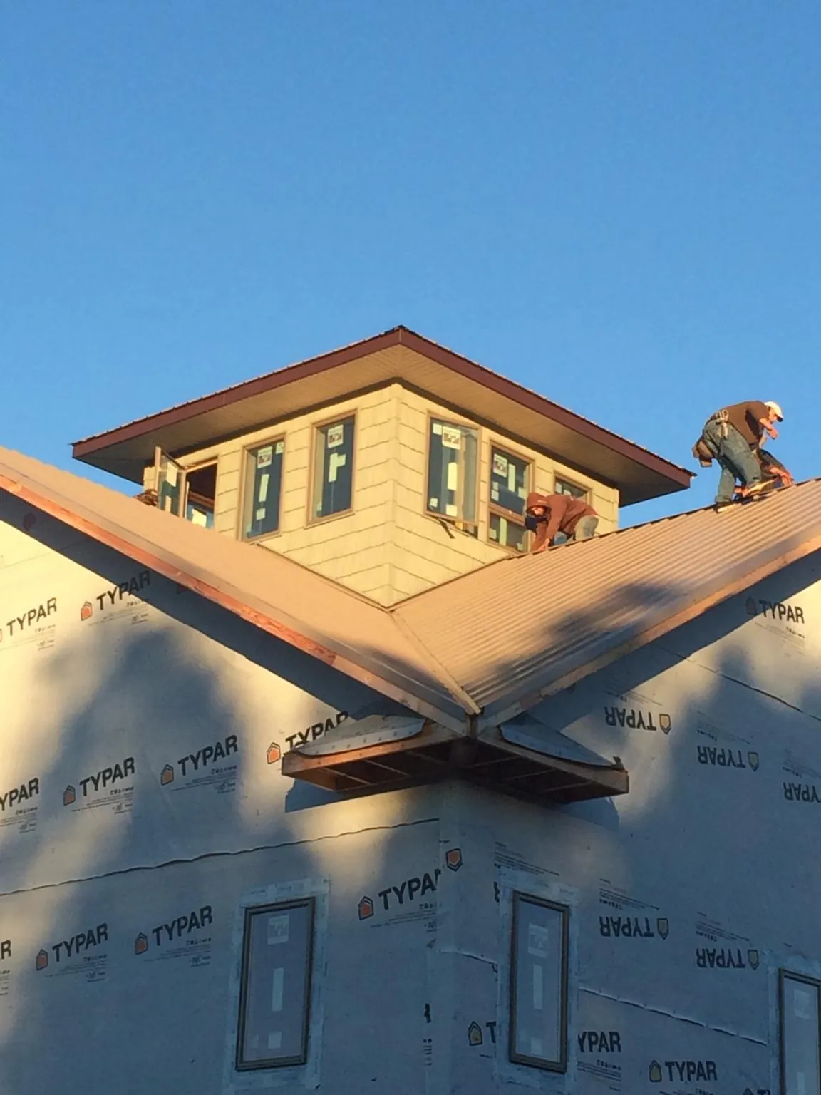 Roofers working around a rooftop cupola on a new metal roof at sunset — Roof Waterproofing in Cottonwood by Roofing Brothers